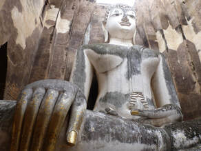 Giant Buddha statue with gold fingernails in the foreground