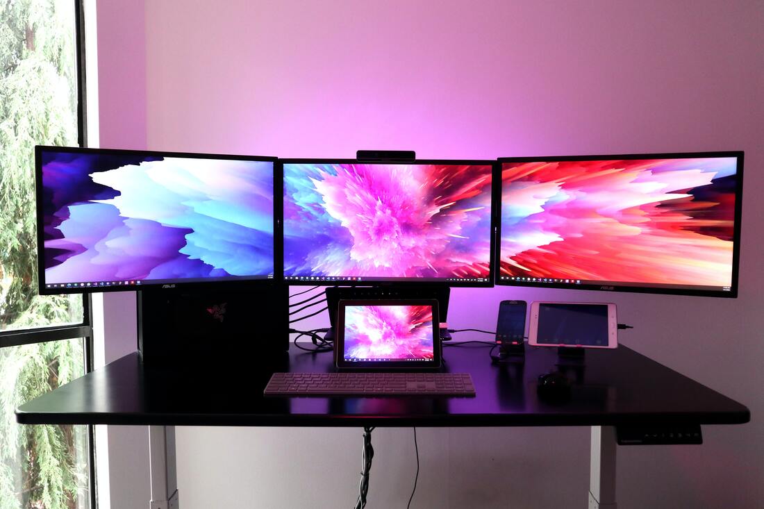 Three large computer monitors with colorful displays