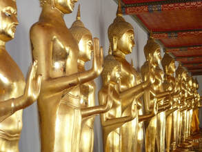 Row of gold Buddha statues, all with one hand extended, face out.